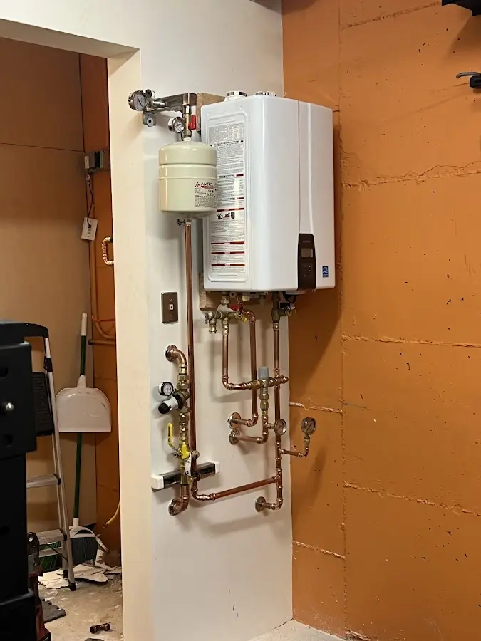 Plumbing technician inspecting water heater connections in Wilbraham